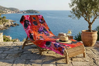 Serviette ATTRACTION drapée sur un fauteuil en rotin face à la mer — Collection Signature ARTGY7